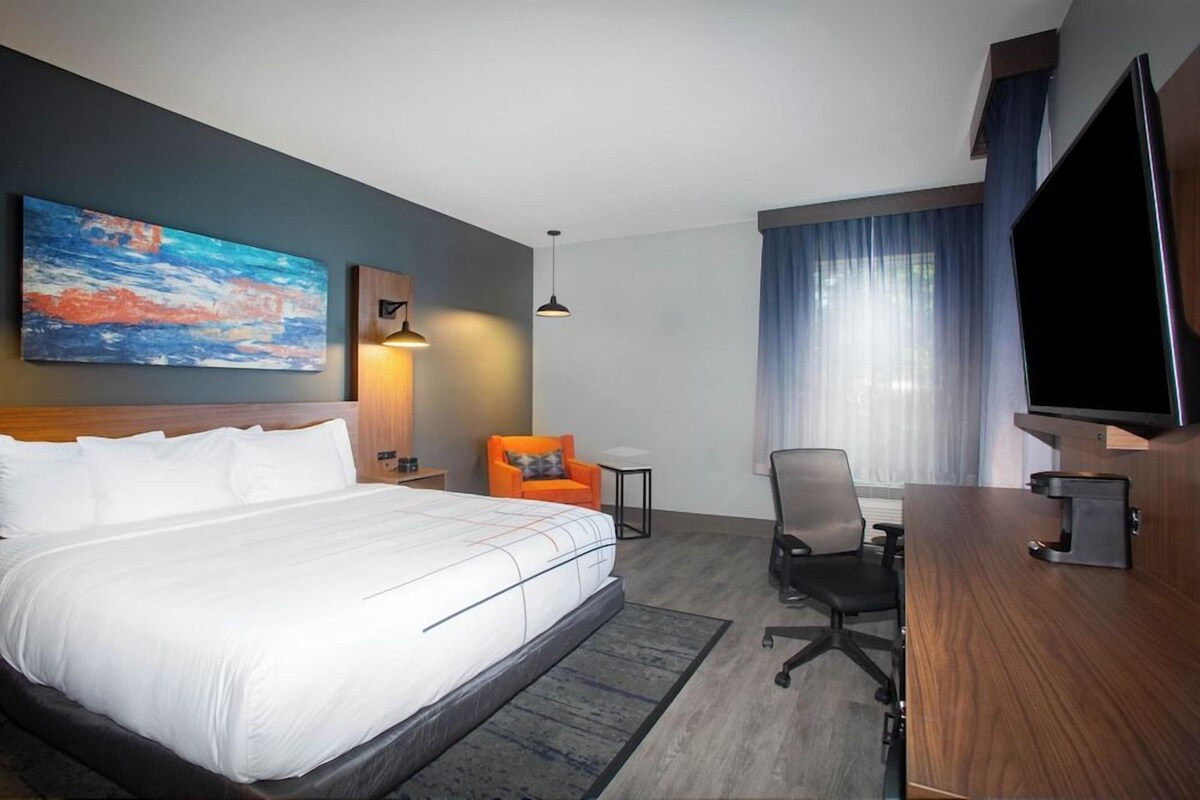 Een hotelkamer met een groot bed, een bureau, een stoel, een televisie en een schilderij aan de wand.