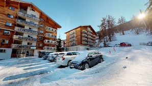 Een hotel met meerdere verdiepingen, balkons en een skipiste op de achtergrond.