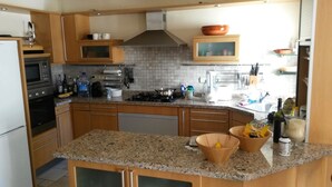 Una cucina moderna con piani di lavoro in granito, mobili in legno, forno integrato e cappa aspirante in acciaio inossidabile.