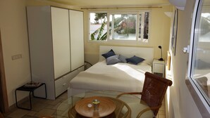 Una camera compatta arredata con un letto, un comodino, una sedia e un tavolino con un bicchiere.