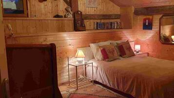 Ein gemütlicher Holzraum mit einem Bett, einem Nachttisch, einer Lampe und einem Spiegel.