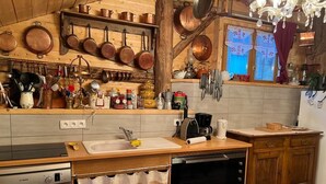 Una cocina con armarios de madera, un lavavajillas Bosch, una cafetera y utensilios de cocina de cobre colgados en la pared.