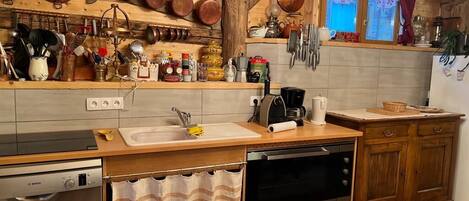 A kitchen with wooden cabinets, a Bosch dishwasher, a coffee maker, and copper cookware hanging on the wall.