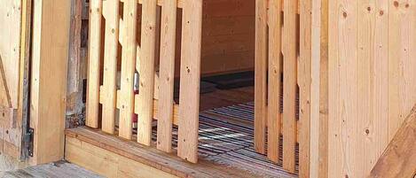 Una cabaña de madera con un porche de madera, una cesta colgada en la pared y un cuadro enmarcado.