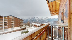 A hotel with multiple floors, balconies, and a view of snow-covered mountains.