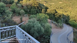 A balcony with a view of a winding road and a mountainous landscape.