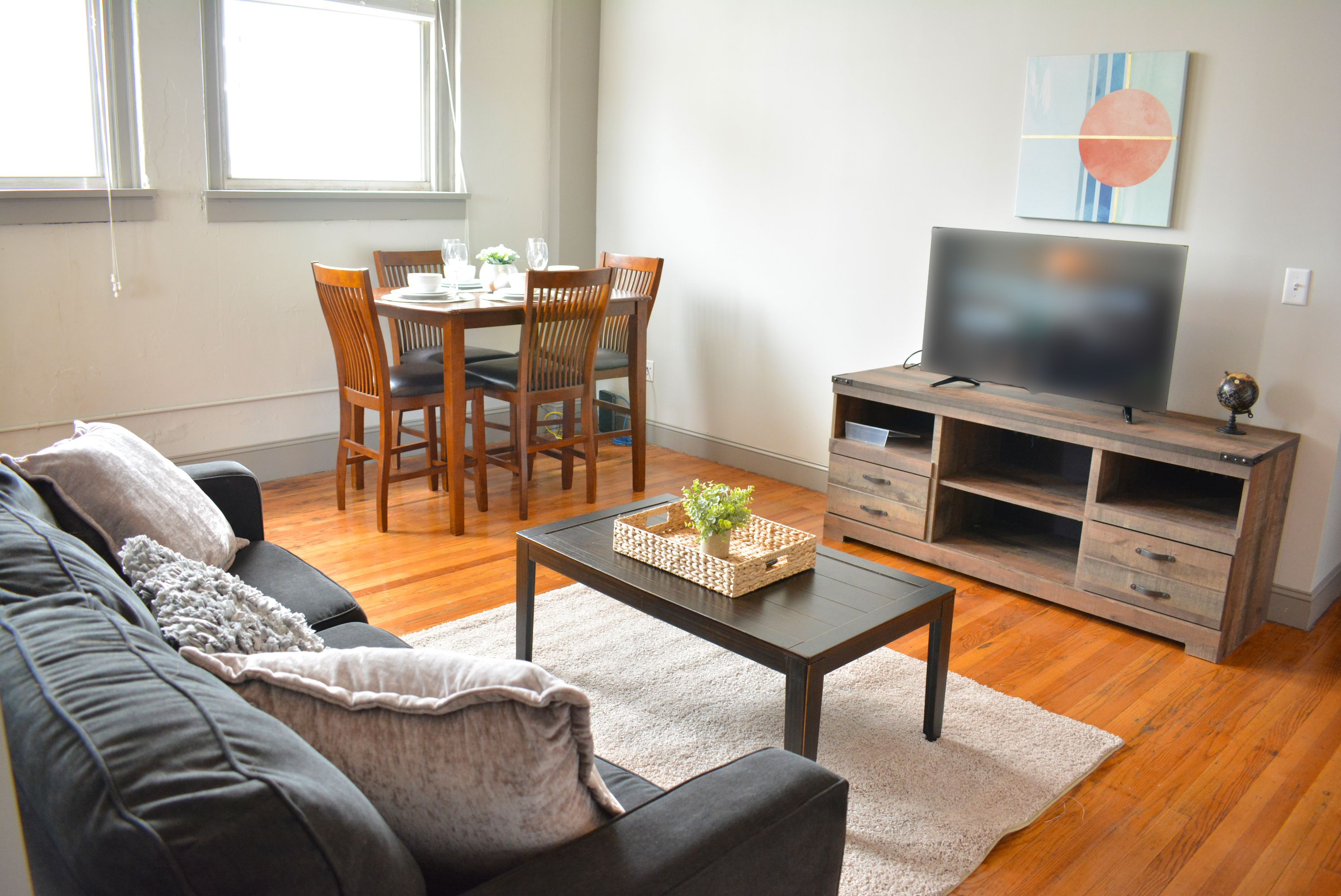 A living room with a sofa, coffee table, TV stand, and dining table with chairs.