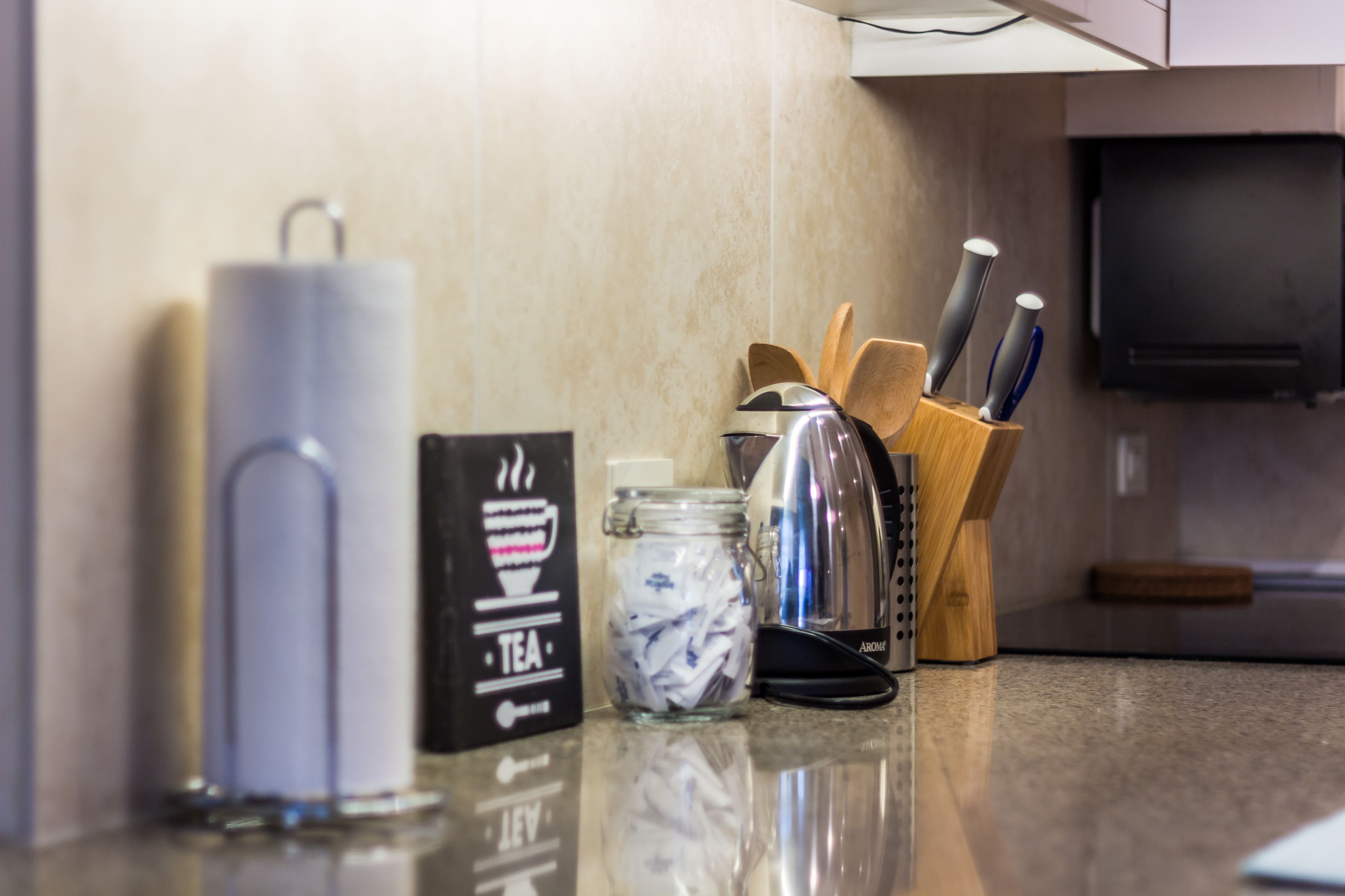 A kitchen counter with a tea infuser, a jar of tea bags, and a knife block.