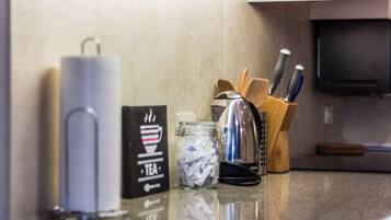 A kitchen counter with a tea infuser, a jar of tea bags, and a knife block.