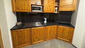 A kitchen with wooden cabinets, a microwave, a coffee maker, and a toaster. - Pracondu 2 001 - OUTDOOR & FUN  charming apartment (Haute-Nendaz)