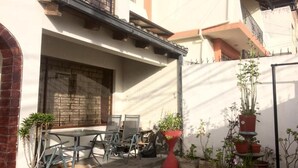 Eine Terrasse mit Tisch und Stühlen, umgeben von Blumentöpfen.