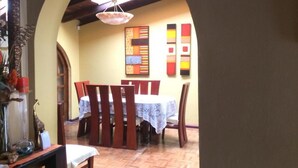 Ein Essbereich mit Tisch, Stühlen, einer Hängelampe und einer Wand mit farbenfroher Kunst.