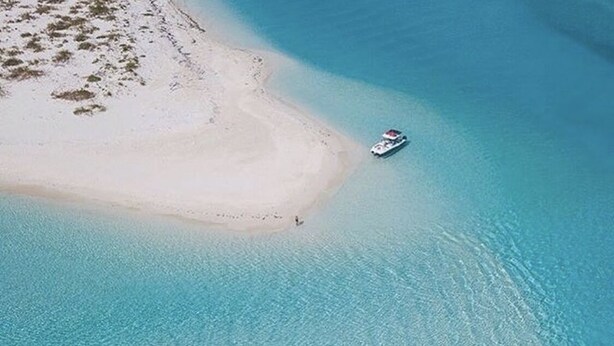 An aerial view of a beach with clear turquoise waters and a small boat near the shore. - SPECIAL DISC, 3BR PRIVATE VILLA, OCEAN VIEW, GREAT AMENITIES, STEPS TO THE BEACH (Long Bay Hills)