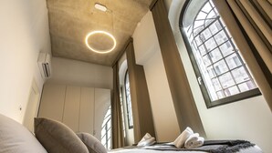 A modern hotel room with a large bed, a circular light fixture on the ceiling, and a view of the city through a large window. - Elegant Fornasa Vecia Canal View R&R (Venecia)