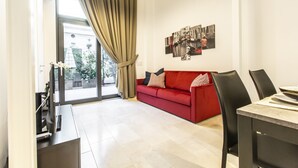 A modern living room with a red sofa, a dining table, and a large window with curtains. - Elegant Fornasa Vecia Canal View R&R (Venecia)