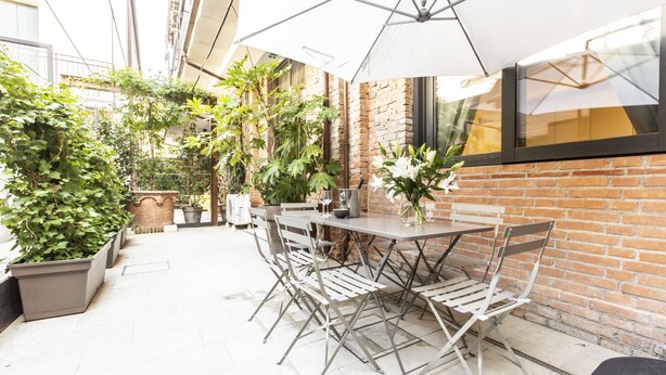 An outdoor patio with a brick wall, a table with chairs, and potted plants. - Elegant Fornasa Vecia Canal View R&R (Venecia)