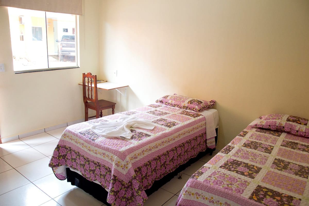 A bedroom with two beds, a chair, and a desk.