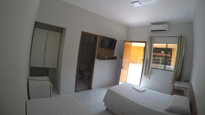 Un dormitorio con cama, armario, baño y ventana con cortinas.