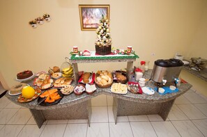 Una mesa de buffet con diversos alimentos y un árbol de Navidad decorado.
