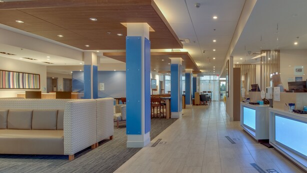 A modern hotel lobby with a reception desk, seating areas, and a large abstract art piece on the wall. - Holiday Inn Express & Suites Union City by IHG (Union City)