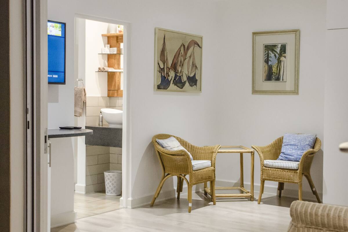 A modern living room with wicker furniture, a flat-screen TV, and artwork on the walls.