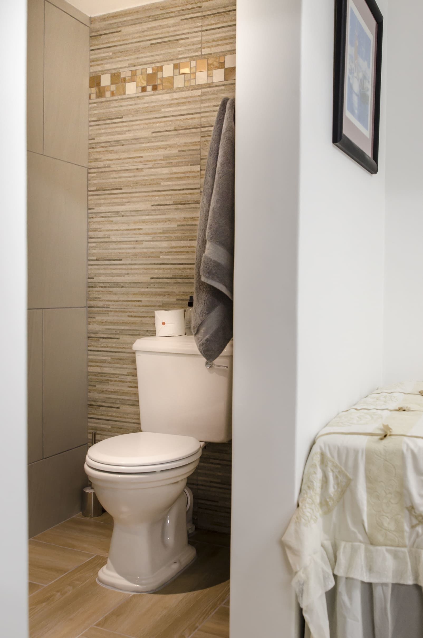 Een badkamer met een toilet, een handdoek aan de muur en een behang met patroon.