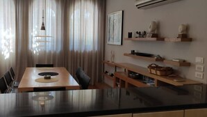 A modern dining area with a wooden table, chairs, and a hanging light fixture. There are shelves with decorative items and a painting on the wall. - Luxury Villa, Scandinavian style,in Golf Solimanya (Giza)
