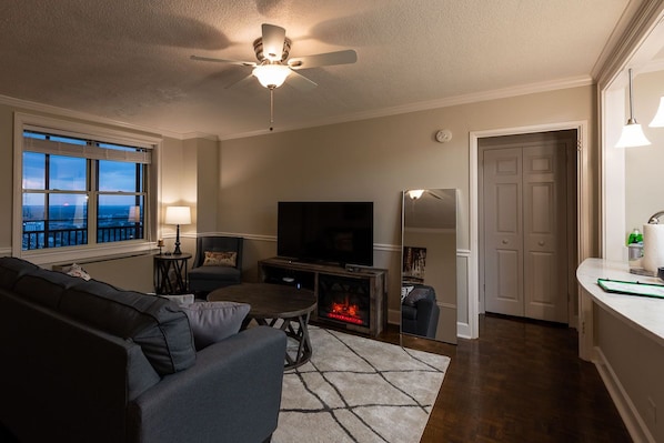 Una sala de estar con sofá, televisión, chimenea y vistas a la ciudad.