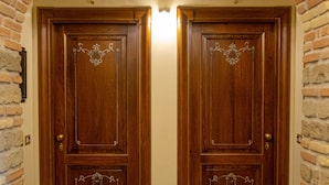 Een houten dubbele deur met decoratieve metalen versiering, begrensd door bakstenen muren en een betegelde vloer.