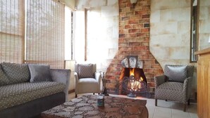A cozy living room with a brick fireplace, patterned sofas, and a coffee table. - Lejartre's Retreat (Mount James)