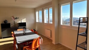 A spacious room with a dining table, chairs, and a black shelf.