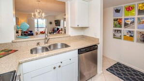 Una cocina con un lavamanos doble, armarios blancos, lavavajillas y un salpicadero decorativo.
