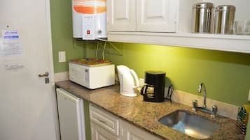 A kitchen with a microwave, coffee maker, and sink.