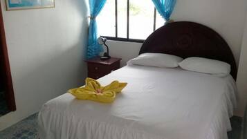 Un letto rifatto con lenzuola bianche e un asciugamano giallo posto alla testata.