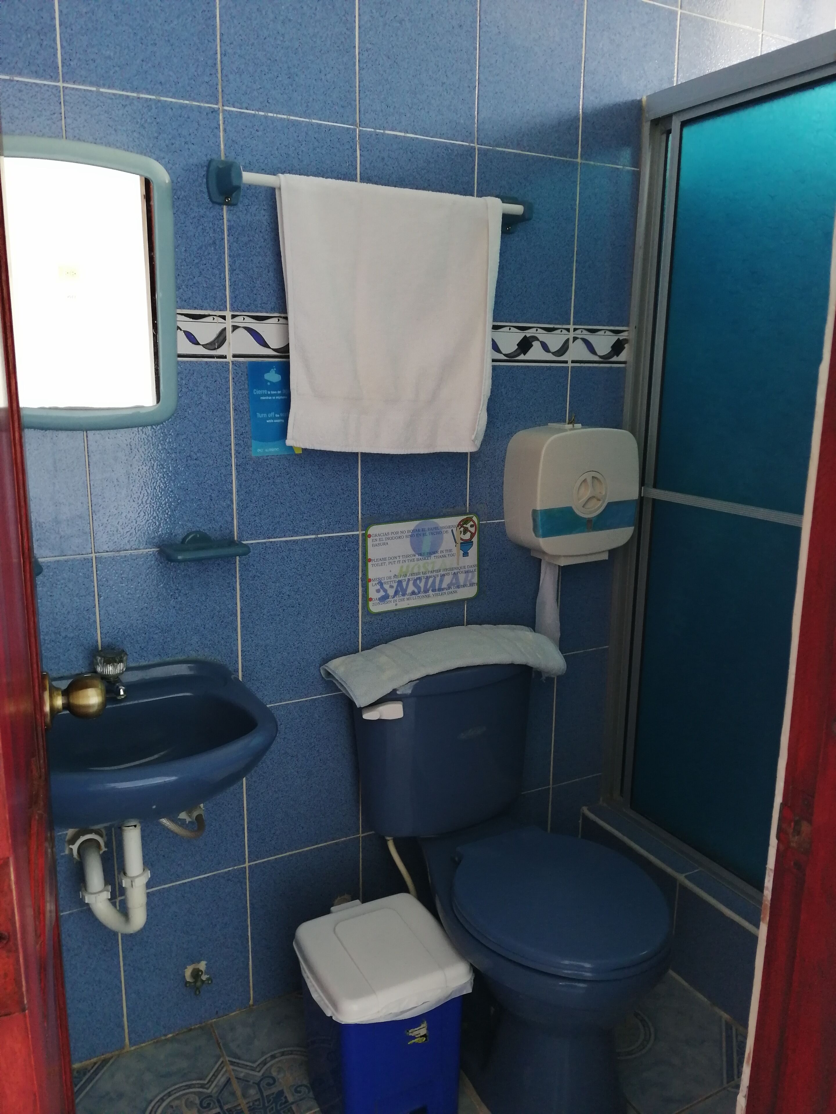 Un baño con lavamanos, inodoro y cubo de basura.