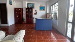 Amplia sala de estar con una isla de cocina azul, un armario de madera y una planta en maceta.