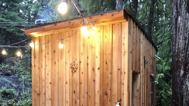Une cabane en bois dotée d’un bain à remous, d’un espace salon extérieur et de guirlandes lumineuses.