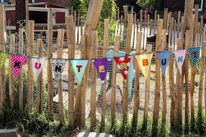 Una cerca de madera con malla de alambre y banderas triangulares de colores que deletrean 'KUTEBUNT'.
