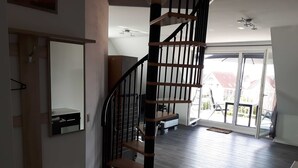 A modern interior with a spiral staircase, a sliding glass door leading to a balcony, and a minimalist design. - Apartment Claudia (Wittmund)