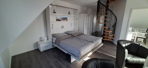 Une chambre à coucher avec un lit, une table de chevet et un escalier.