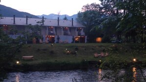 A riverside hotel with a grassy area and outdoor seating. - Moon River Suites 1 - on River, Private Hot Tub, No Flood Impact (North Bend)