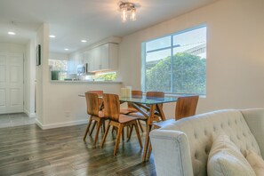 A modern kitchen with white cabinets, a glass dining table, and wooden chairs. - Moon River Suites 1 - on River, Private Hot Tub, No Flood Impact (North Bend)