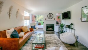 A modern living room with a leather sofa, glass coffee table, and a fireplace. - Moon River Suites 1 - on River, Private Hot Tub, No Flood Impact (North Bend)