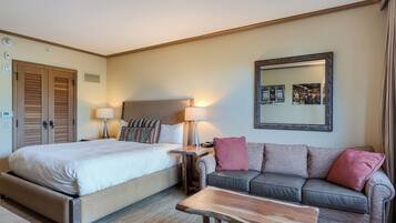 Une chambre d’hôtel avec un grand lit, un canapé, une table basse, une lampe et un miroir au mur.