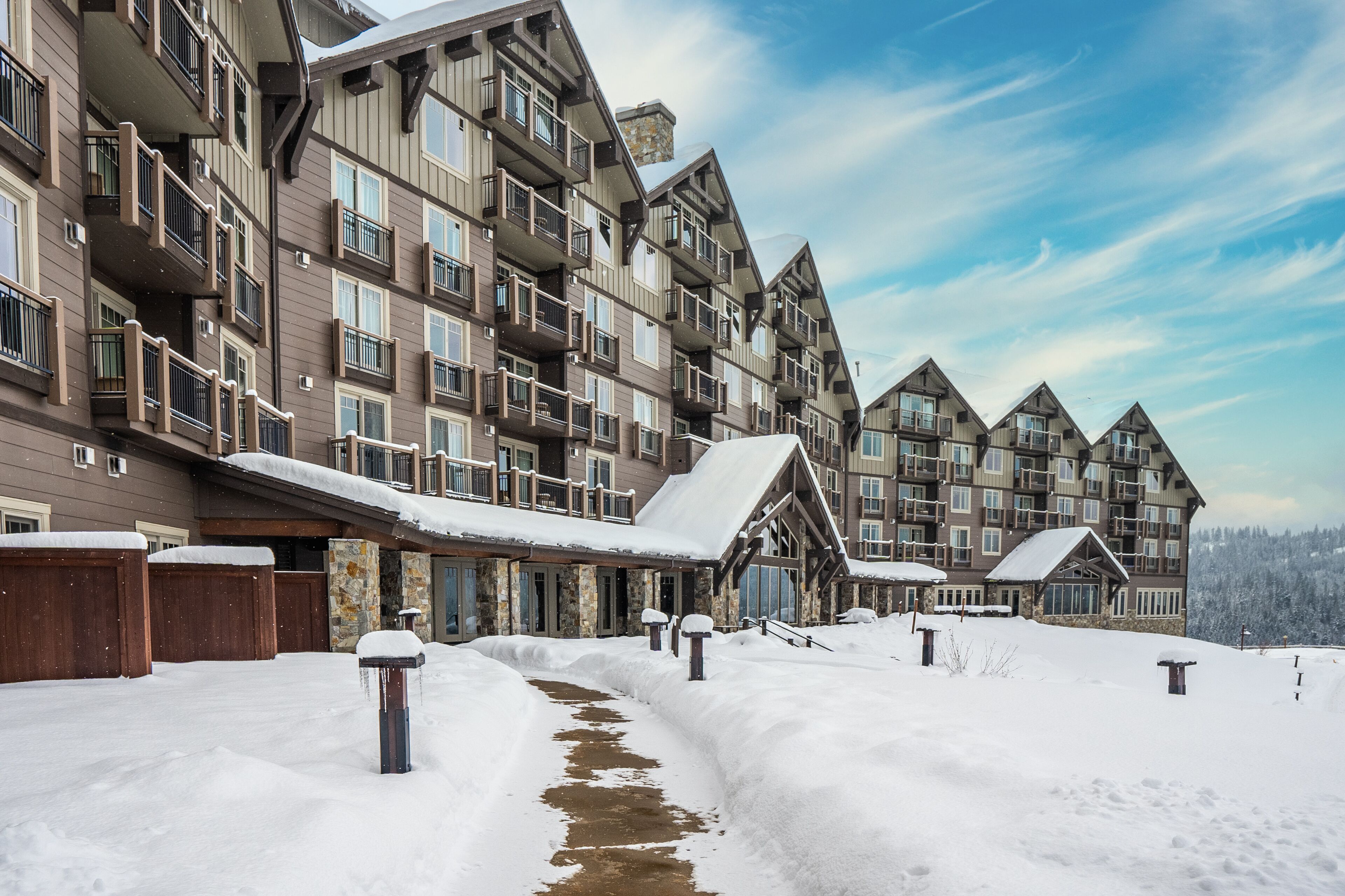 A multi-story hotel with balconies, a snow-covered entrance, and a clear sky.