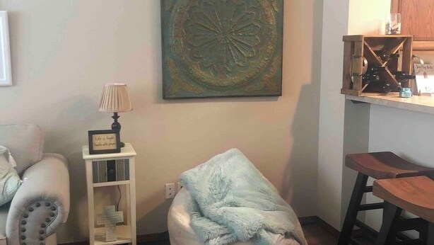 A cozy living room with a bean bag chair, a small table, and a wall-mounted shelf. - Cute, cozy, close duplex. (Stillwater)