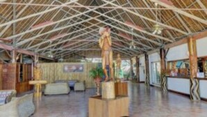 Un vestíbulo espacioso con techo alto, vigas de madera y una zona de estar central con sofás y una mesa de centro.
