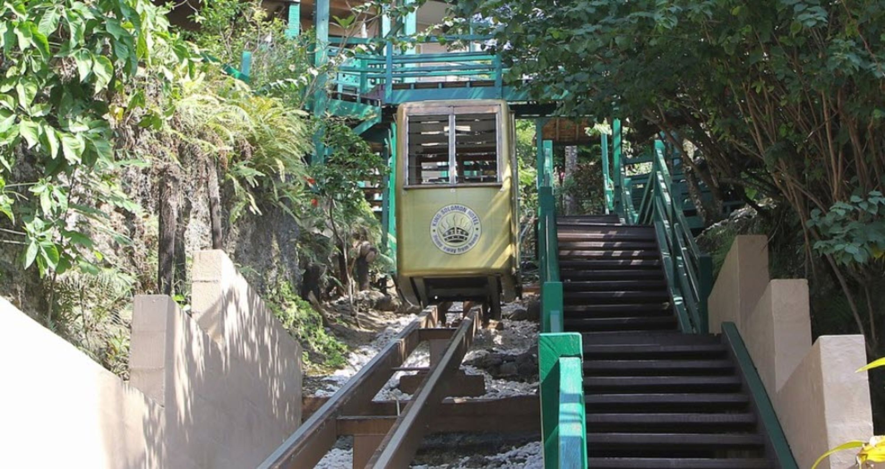 Una estación de tren con una escalera verde que sube a un andén.