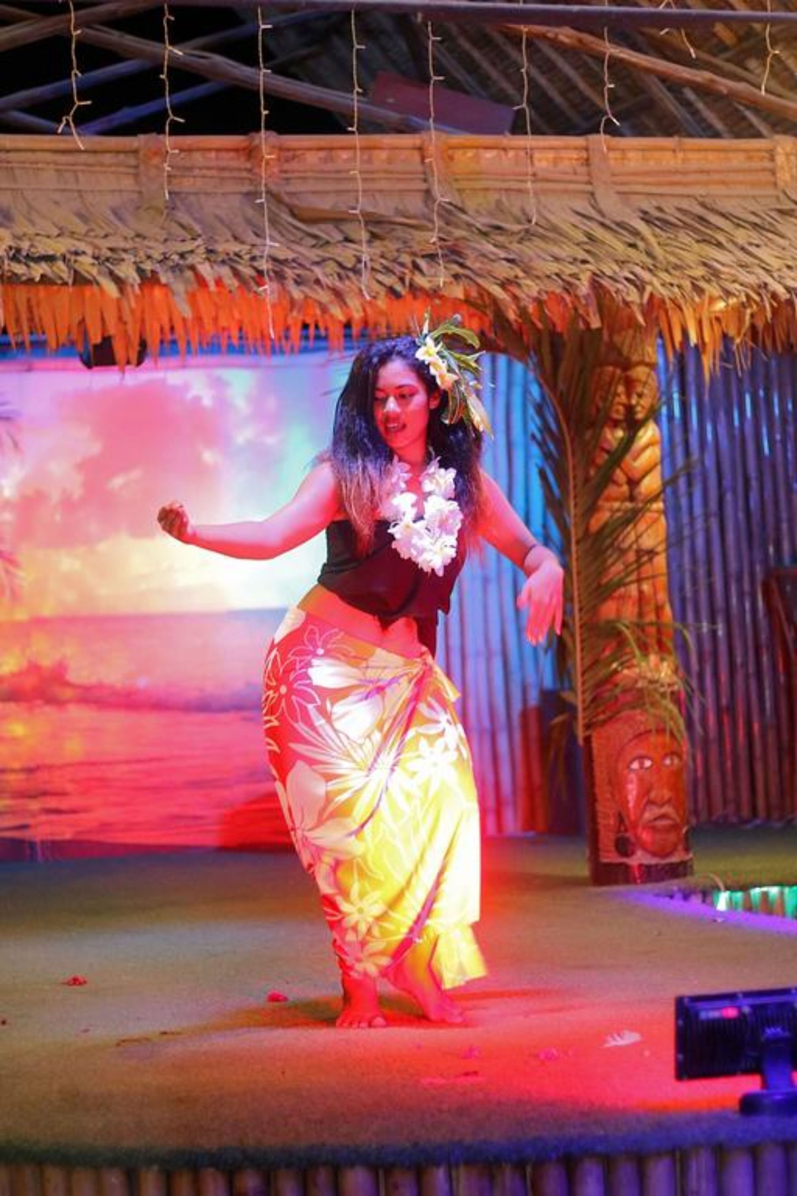 Una persona actuando en un escenario con un fondo tropical.