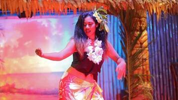 Una persona actuando en un escenario con un fondo tropical.